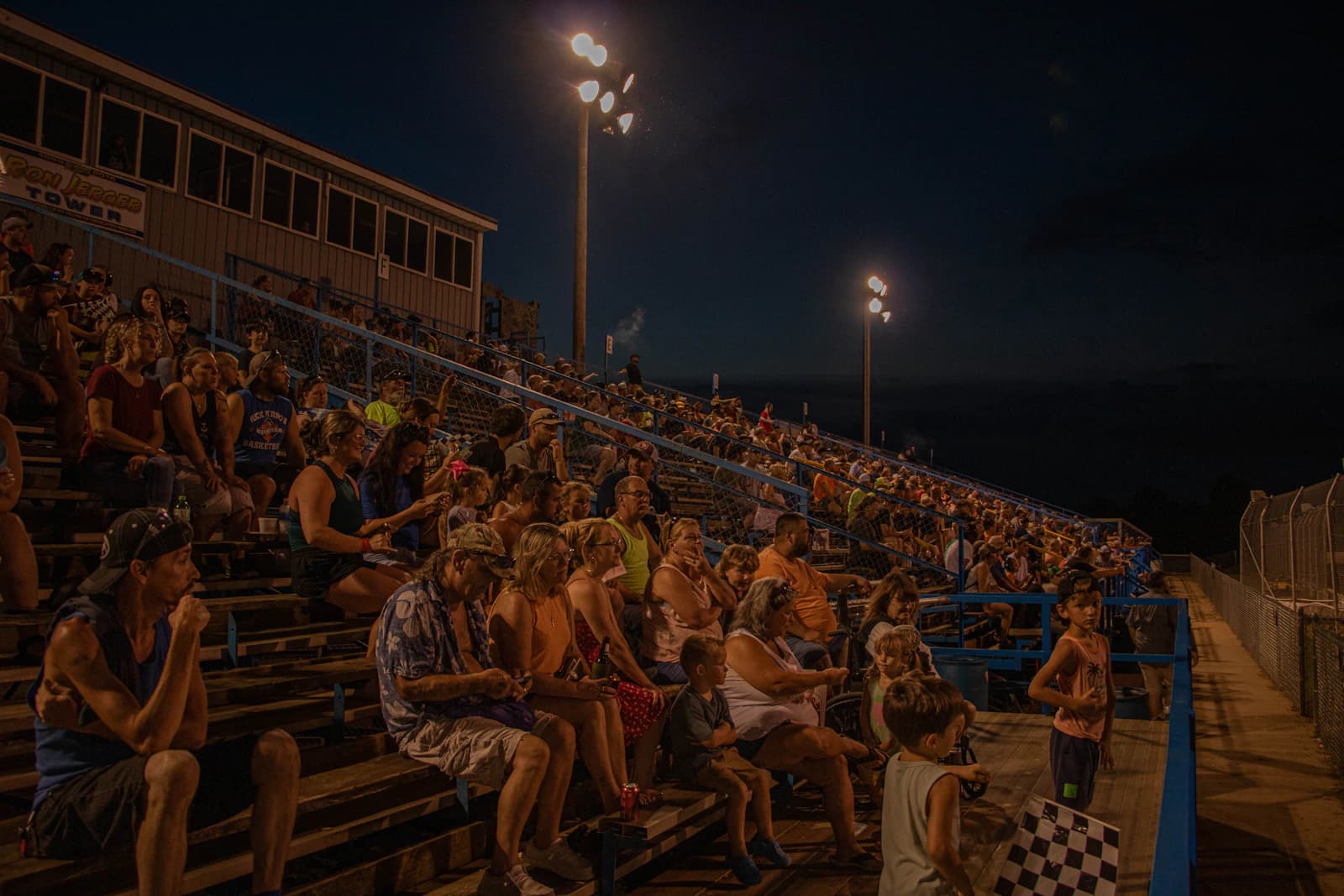 Packed stadium bleachers at night lit by arena lights